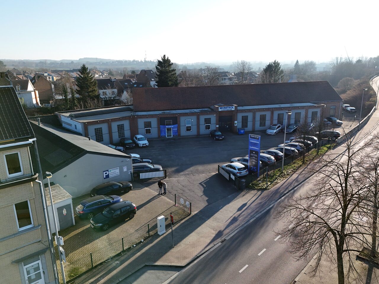 Luchtfoto van de carrosserie van Wonitrol op Stationsstraat 25 — werkplaats, parking, totem aan de straat.